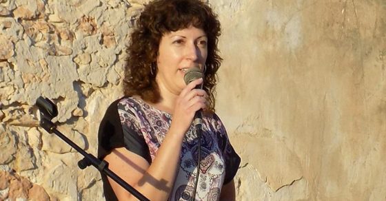 Maria Teresa Ferrer habla ante un micrófono junto a un muro de piedra