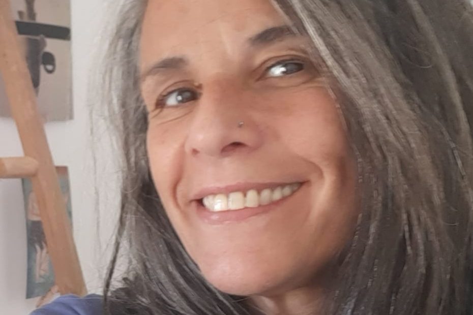 Autorretrato de Nora Almada, sonriente, con el pelo largo y canoso