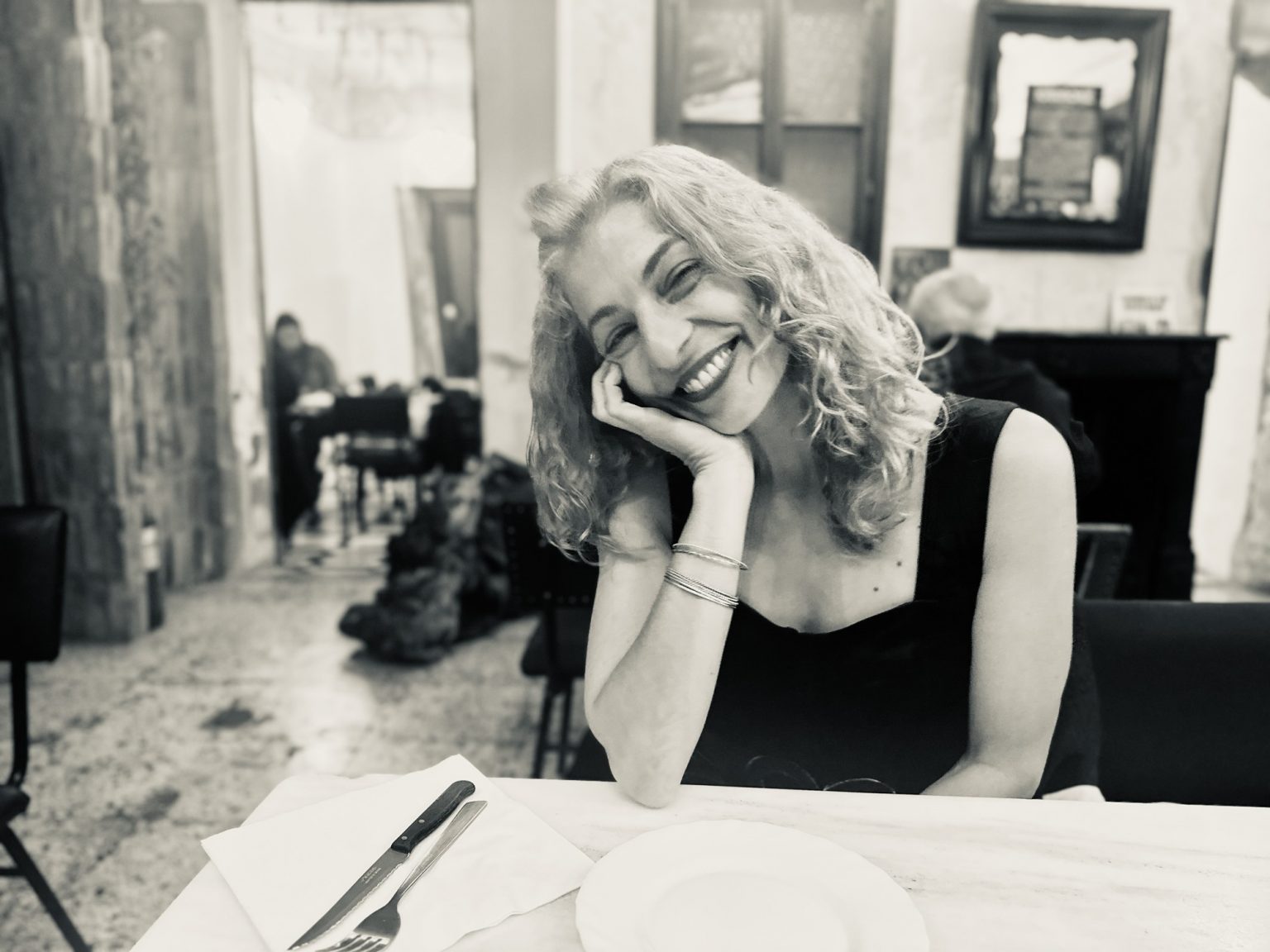 Roser Amills en blanco y negro, sentada a una mesa con la mano en la mejilla