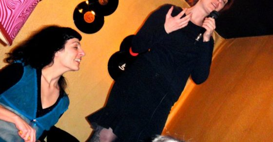 La performer Barbara Kuzma, de negro, y Roser Amills con micrófono en un escenario con discos de vinilo