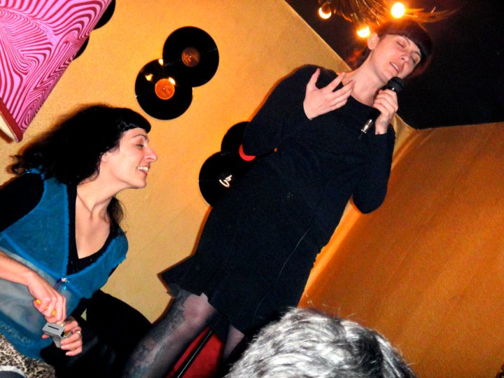 La performer Barbara Kuzma, de negro, y Roser Amills con micrófono en un escenario con discos de vinilo