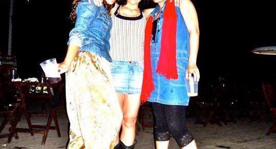 Tres mujeres posan de noche en una terraza de madera, entre ellas Roser Amills y Lídia Penelo