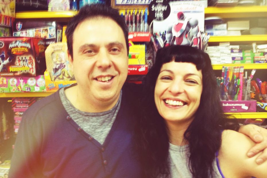 Roser Amills y Octavi Serret abrazados en una librería con estantes de juguetes y papelería