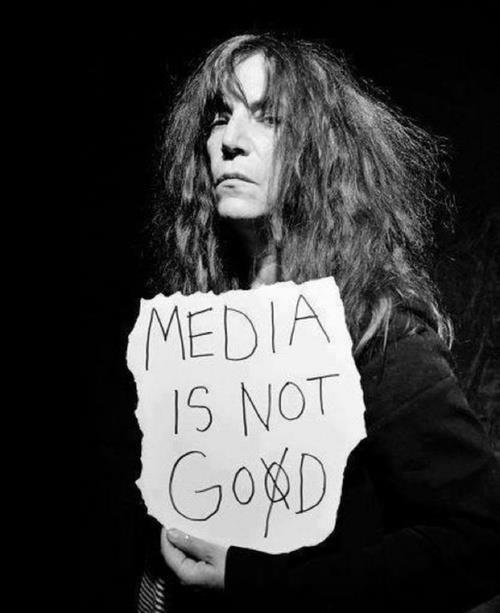 Patti Smith en blanco y negro sosteniendo un papel con las palabras «Media is not good»