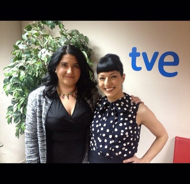Carmen García y Roser Amills, con vestido de lunares, de pie ante el logo de TVE