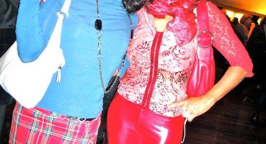 Roser Amills, con falda escocesa, y Regina do Santos, con pantalón rojo de charol y gorro rojo, en una fiesta
