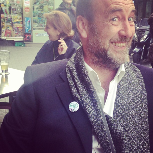 Emili Manzano, somrient, amb mocador i xapa a la solapa, en una terrassa