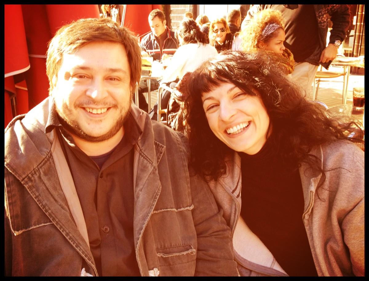 Roser Amills y el escritor Hernán Casciari, con cazadora marrón, sonríen en una terraza soleada
