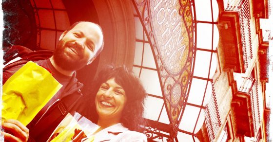 Roser Amills y Miguel Noguera sonrientes con bolsas amarillas bajo una cúpula de cristal