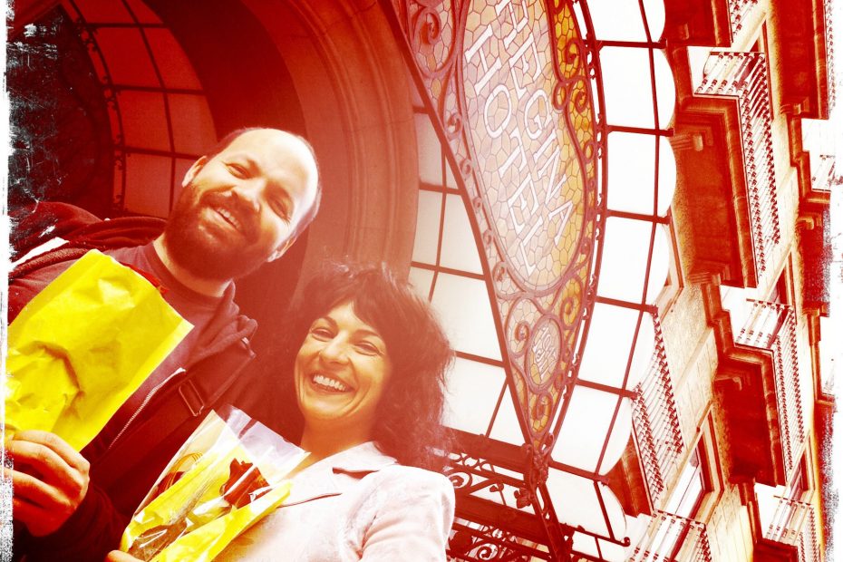 Roser Amills y Miguel Noguera sonrientes con bolsas amarillas bajo una cúpula de cristal