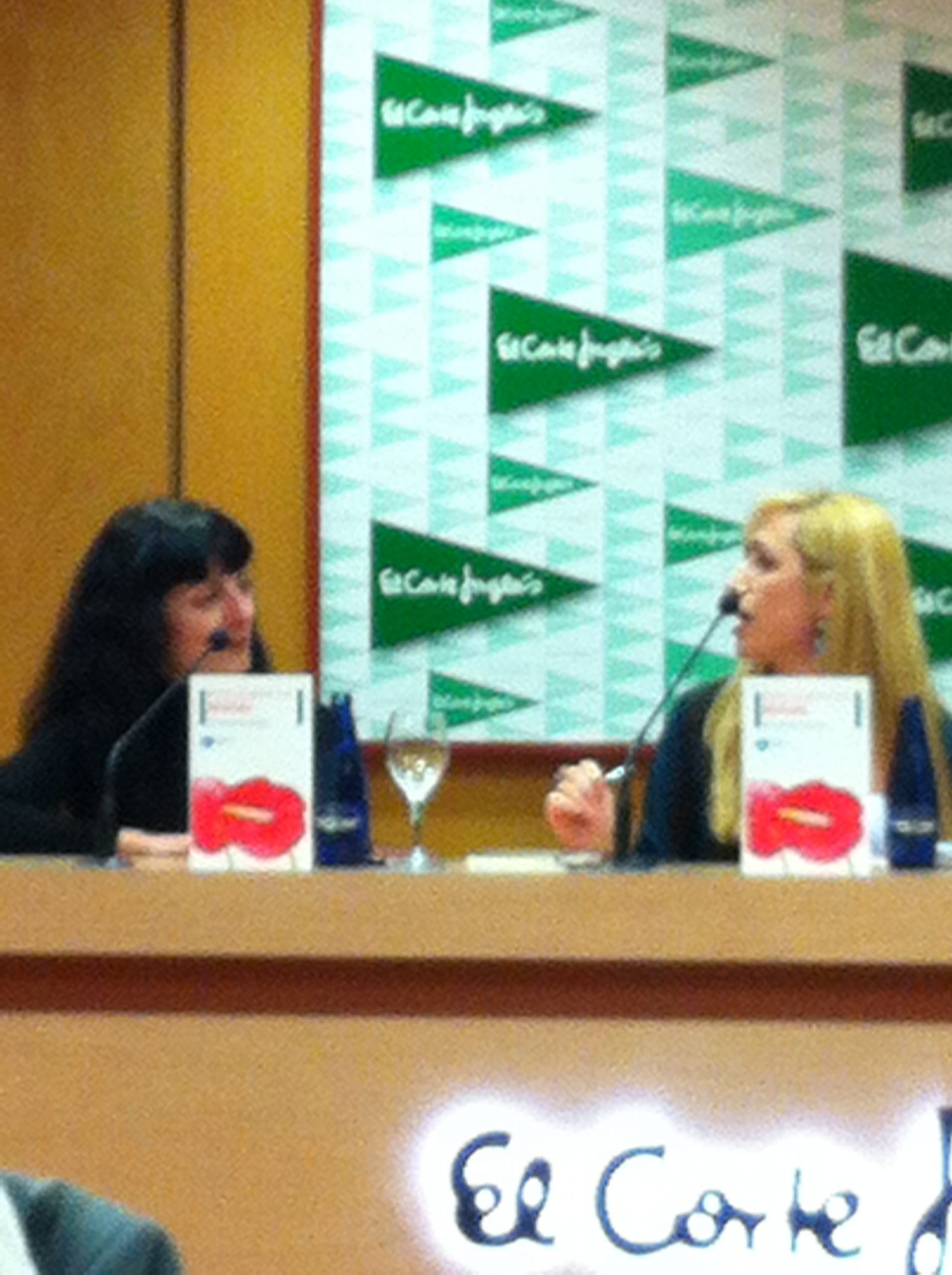 Roser Amills y Sílvia Soler, sentadas tras una mesa con micrófonos ante un panel de El Corte Inglés