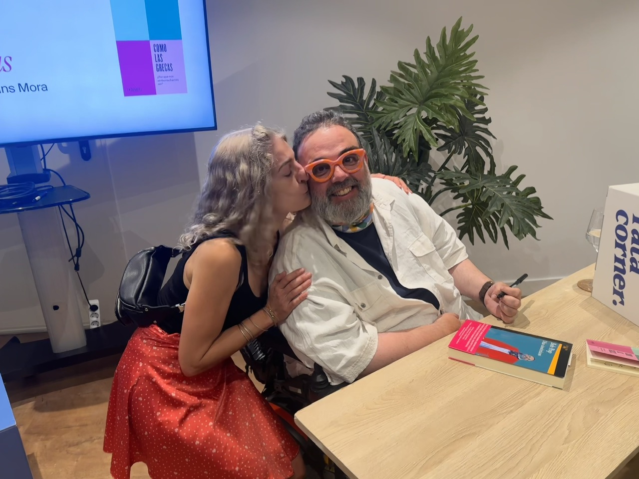 Roser Amills da un beso a Bob Pop, que lleva gafas rojas, en la mesa de firmas