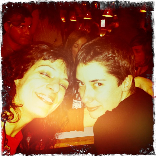 Selfi de Sílvia Bel y Roser Amills en un bar lleno de gente con luz roja