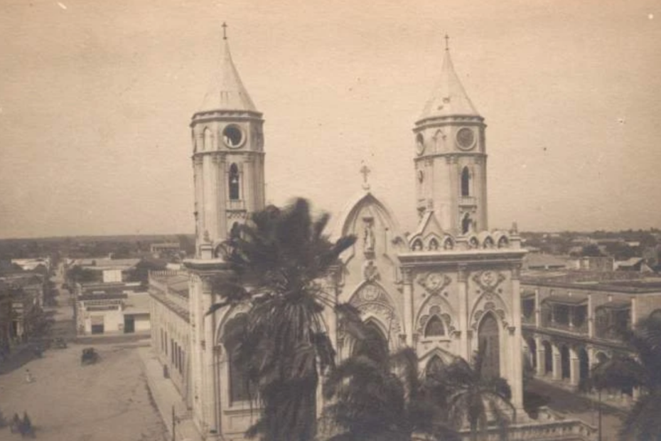 La iglesia neogótica de San Nicolás de Tolentino, con sus dos torres y palmeras delante, y la plaza de tierra a un lado, hacia 1910