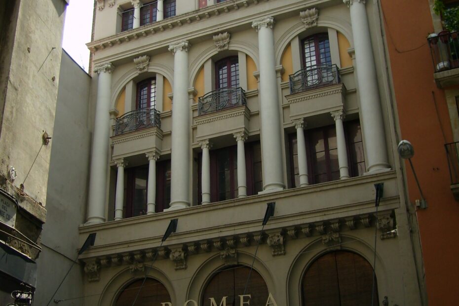 Fachada del Teatre Romea en la calle del Hospital de Barcelona, con columnas, balcones y el rótulo del teatro sobre la marquesina