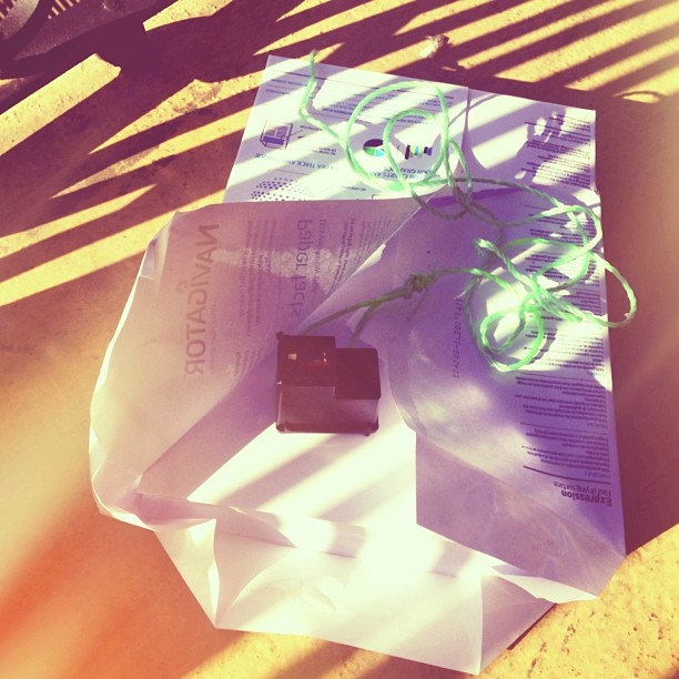 Cartucho de tinta Navigator sobre una bolsa de papel y un cordel verde, a la luz del sol