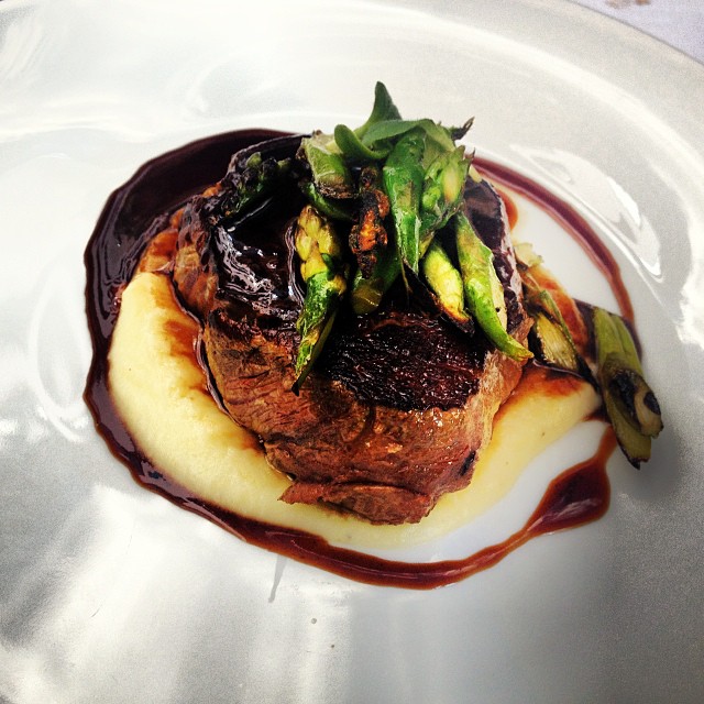 Plato de carne con puré de patata, salsa oscura y espárragos