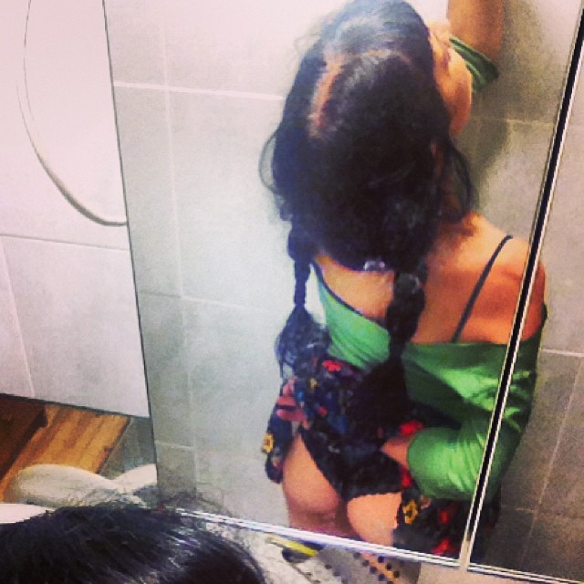 Foto de Amills Public WC: una mujer de espaldas, con trenzas, ante el espejo de un cuarto de baño
