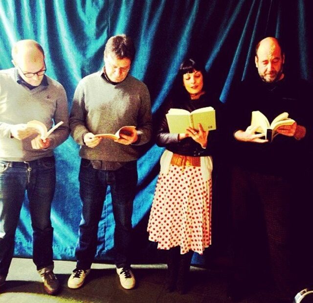 Roser Amills con tres hombres leyendo un libro cada uno, de pie ante una cortina azul, en El plaer de la lectura
