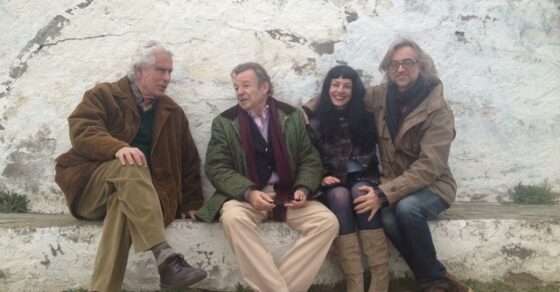 Roser Amills sentada con tres hombres en un muro encalado de Cadaqués