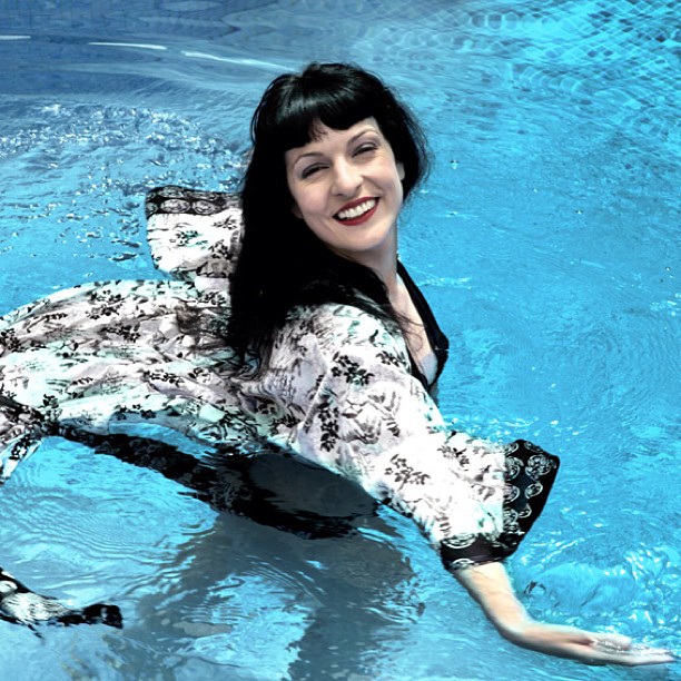 Roser Amills sonriendo dentro del agua de una piscina con un kimono estampado