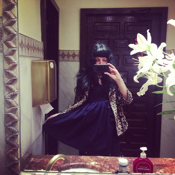 Roser Amills haciéndose un selfi en el espejo de un lavabo con un ramo de lirios blancos