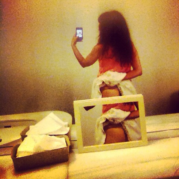 Autorretrato en el espejo de un lavabo con una falda recogida