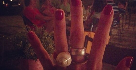 Mano con las uñas rojas y un anillo nuevo de caracola