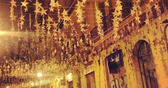 Calle de Gràcia de noche decorada con estrellas doradas por las fiestas