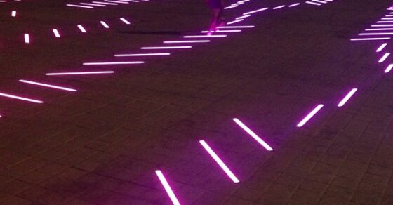 Plaza con líneas de luces led fucsia en el suelo de noche