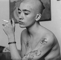 Retrato en blanco y negro de Alberto García-Alix: mujer rapada y tatuada fumando