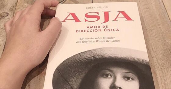 Ejemplar de Asja. Amor de dirección única sobre una mesa de madera, junto a un vaso con una bebida verde y la mano de una lectora