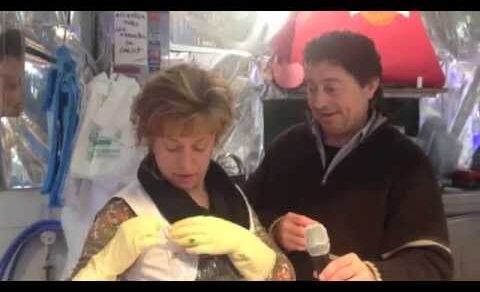 Una pareja entrevistada por Roser Amills en un puesto del Mercat de l’Abaceria de Gràcia