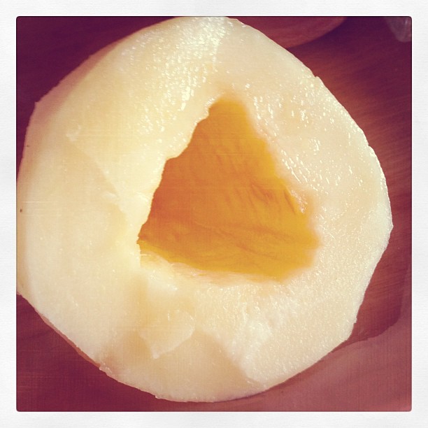 Fruta pelada, de pulpa blanca, con un hueco triangular que deja ver una pulpa amarilla