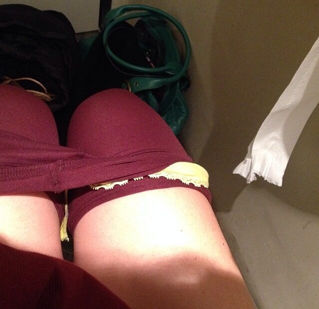 Piernas de Roser Amills con medias granates y bragas amarillas, sentada junto a un bolso verde