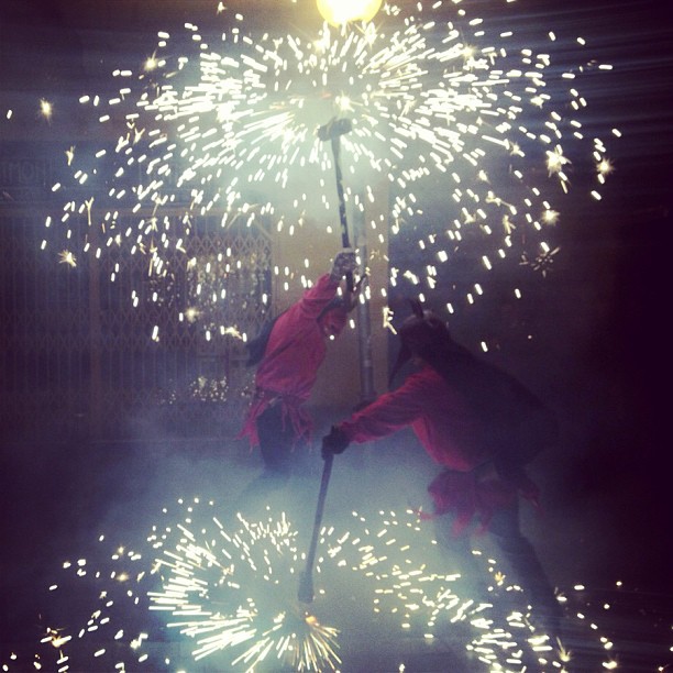 Dos diablos de correfoc entre una lluvia de chispas de fuegos artificiales