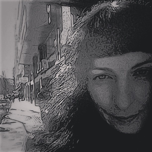 Autorretrato en blanco y negro con efecto de grano, con un gorro de orejas y una calle al fondo