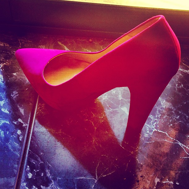 Zapato de tacón fucsia sobre un suelo de mármol