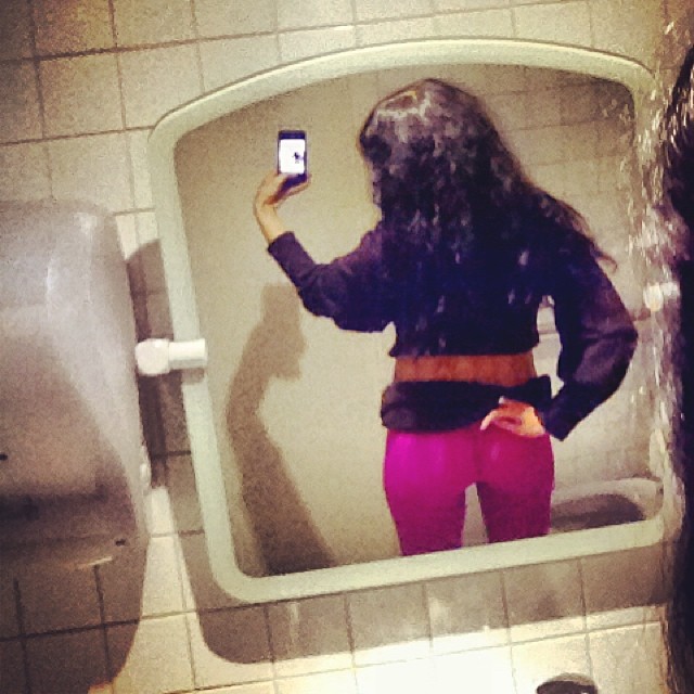 Roser Amills, de espaldas y con pantalón rosa, se hace un selfie con el móvil en el espejo de un lavabo