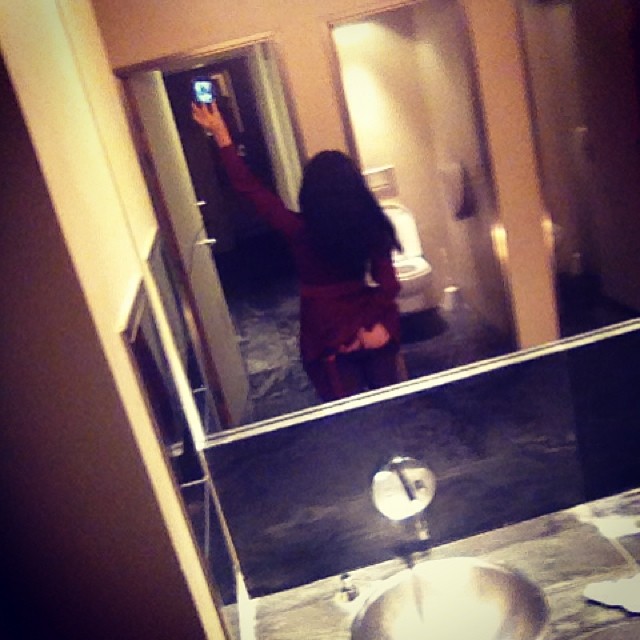 Roser Amills, de espaldas, se hace una foto con el móvil en el espejo de un lavabo