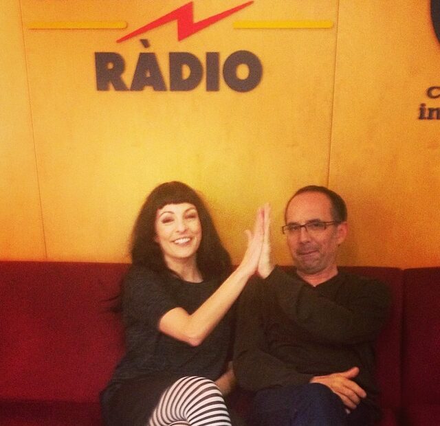 Roser Amills i Toni Orensanz xocant les mans en un sofà vermell davant el logotip de Catalunya Ràdio