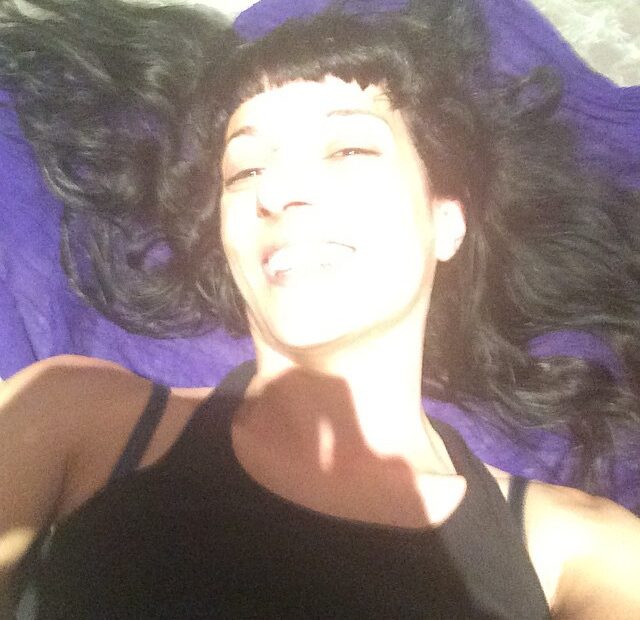 Selfi de Roser Amills sonriendo, con el pelo suelto sobre una tela morada