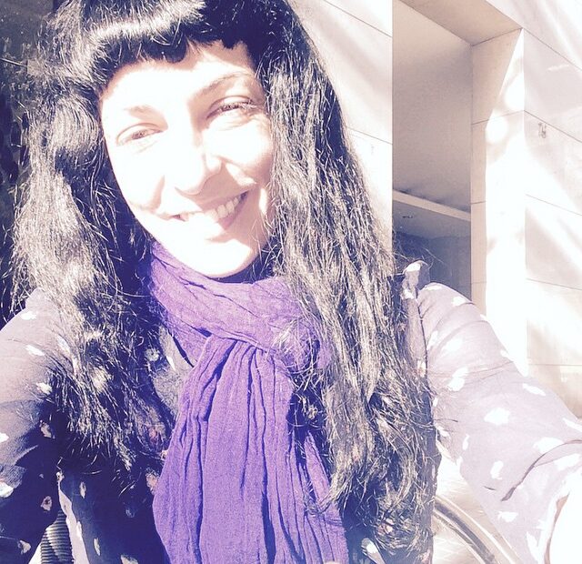 Selfi de una mujer sonriente con el pelo largo y negro y una bufanda morada