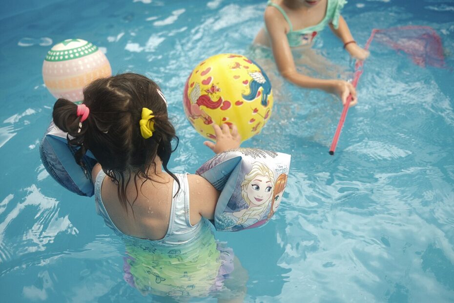 Niños jugando en una piscina con manguitos de colores
