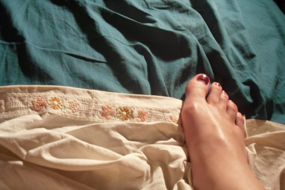 Los pies de Roser Amills con las uñas pintadas, sobre las sábanas de una cama