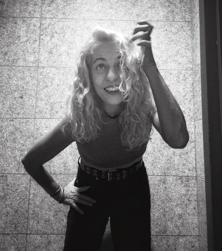 Retrato en blanco y negro de Roser Amills, de pie y sonriente.