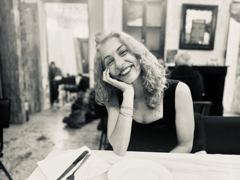 Retrato en blanco y negro de Roser Amills con la mano en la mejilla, sentada a la mesa de un café.