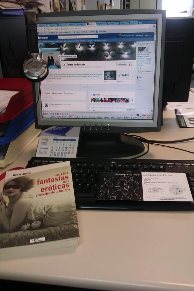 Escritorio con un ordenador y el libro Las 1.001 fantasías más eróticas y salvajes de la historia