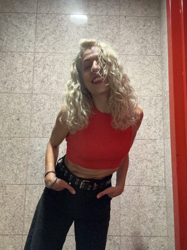 Roser Amills, con top rojo y pantalón negro, ante una pared de granito.