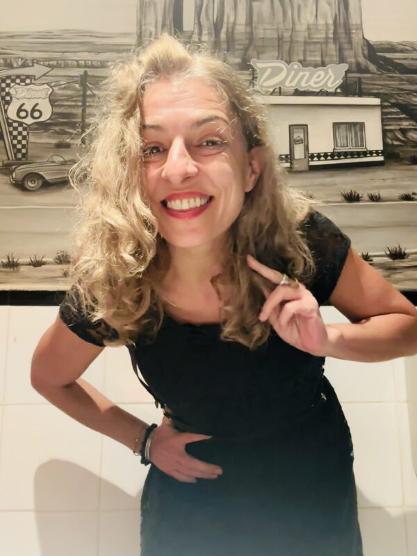 Roser Amills, con vestido negro, sonríe y señala a cámara.